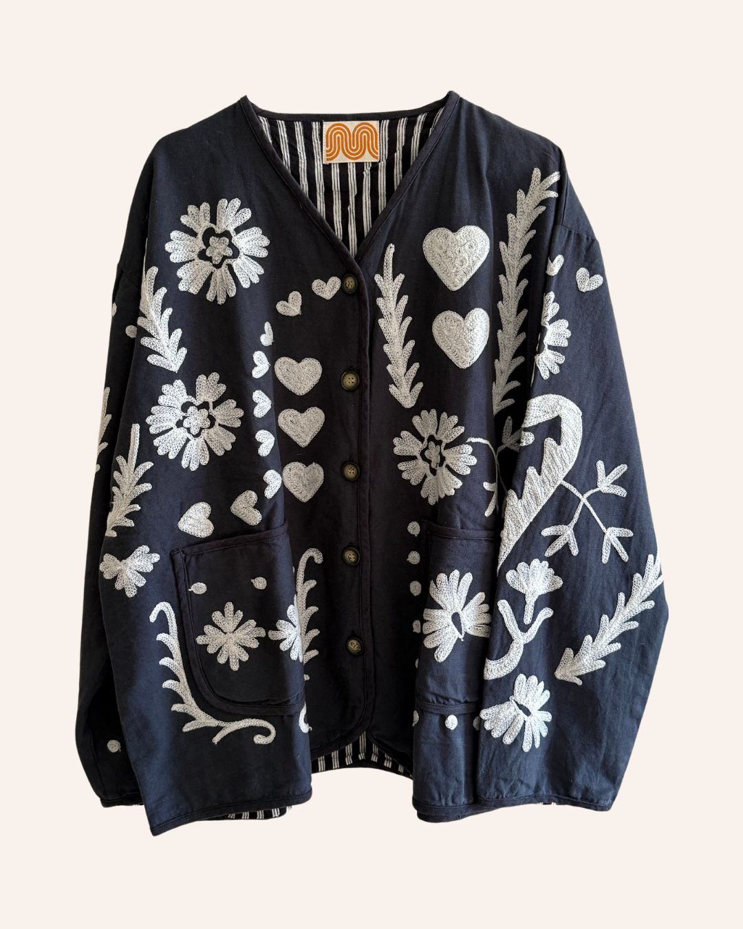 Front of black embroidered jacket with ivory flowers, hearts, and patch pockets