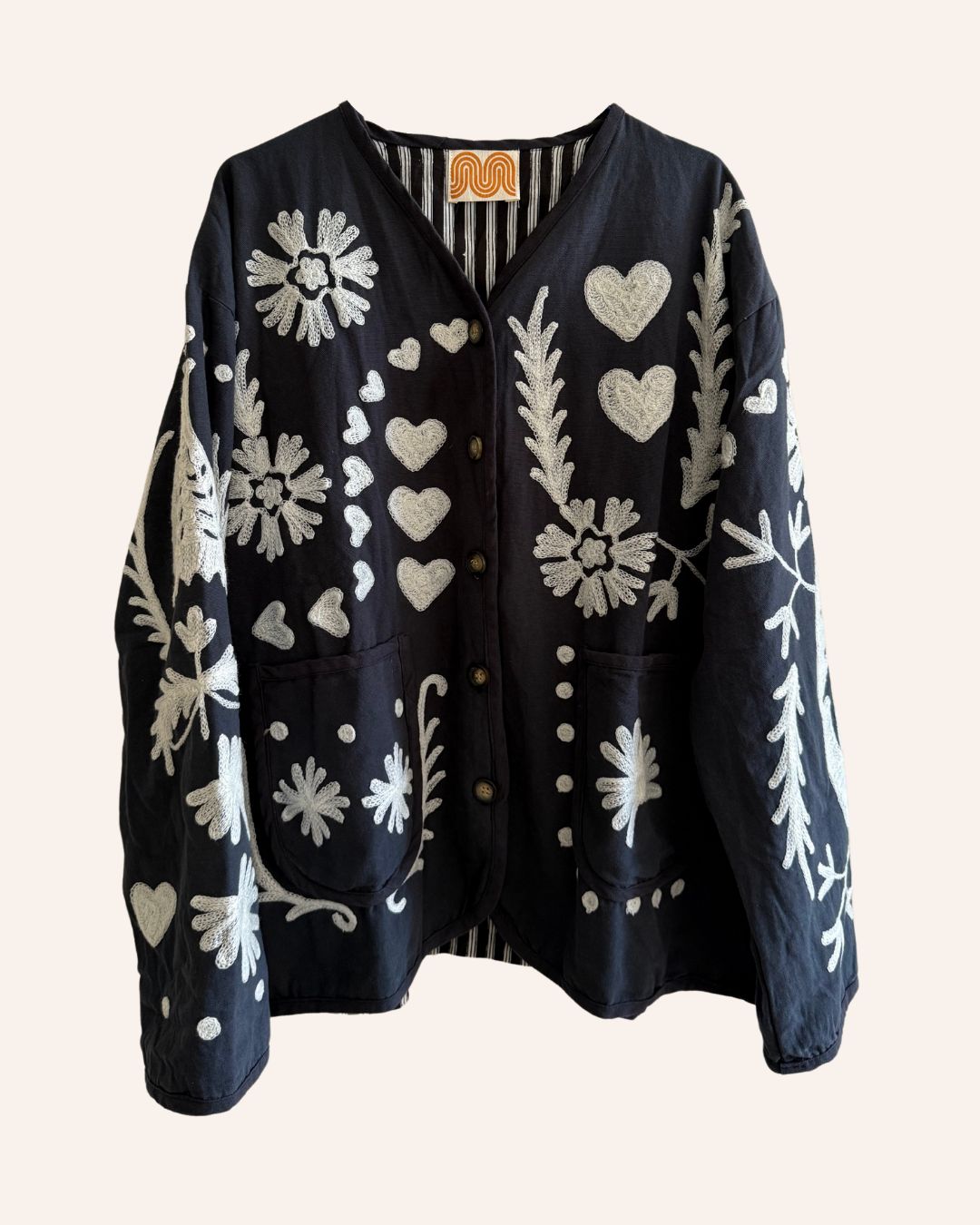 Front of black jacket with ivory embroidery, hearts, florals, and striped lining