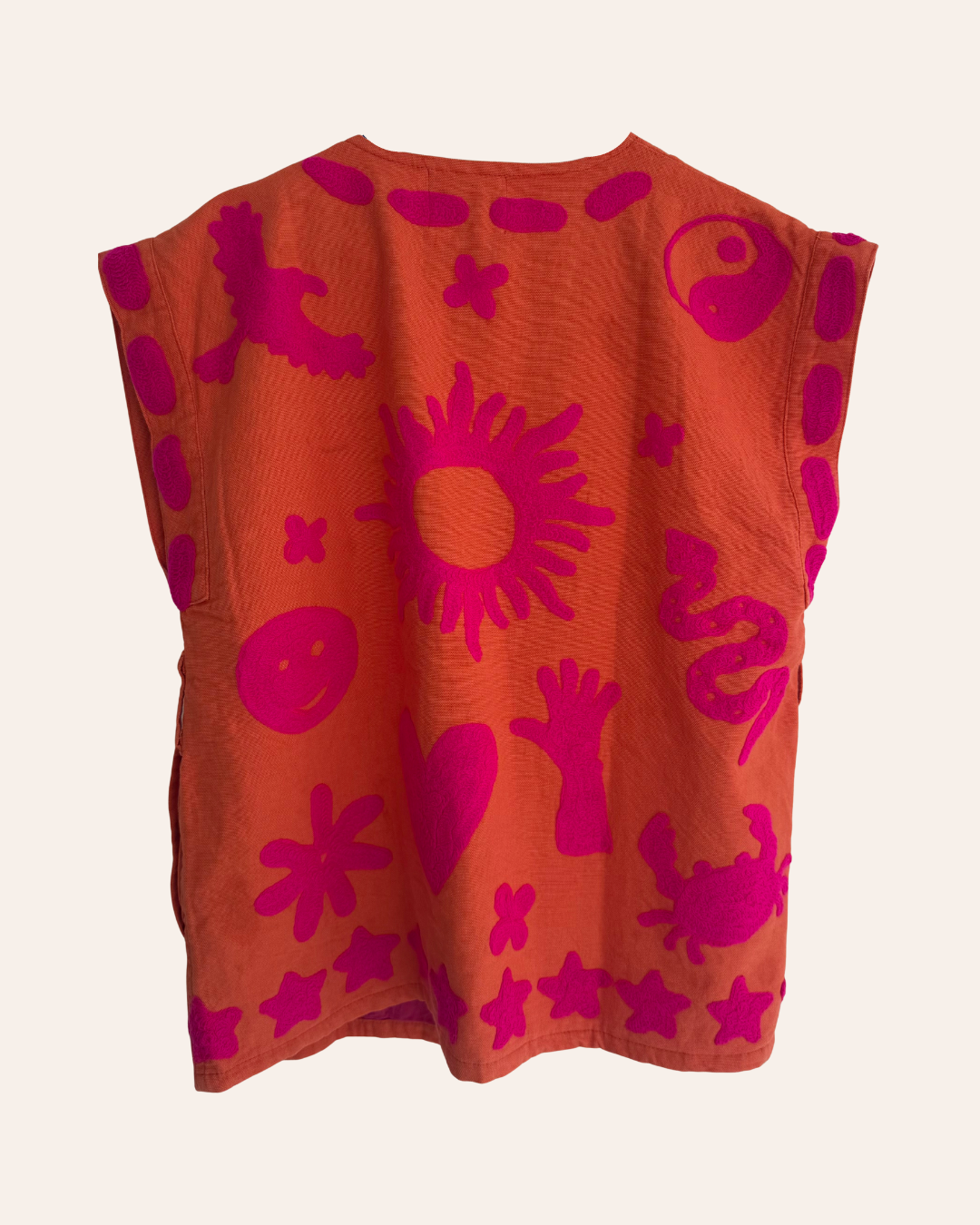 Hand-embroidered orange summer vest with pink playful symbols including crab, heart, flower, and yin-yang. back