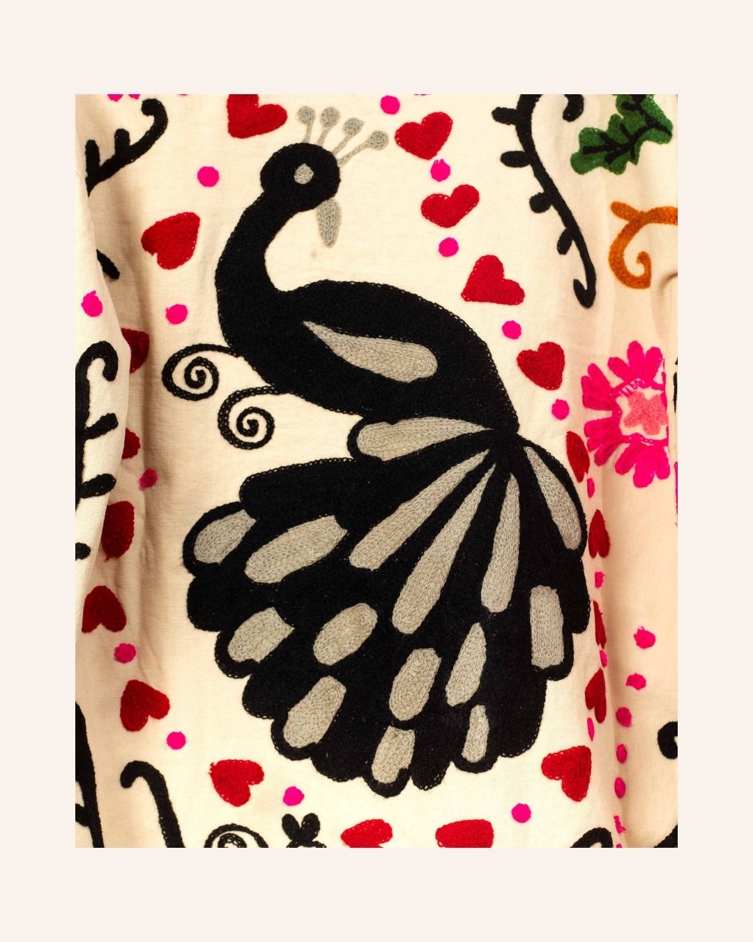 Cream cotton jacket hand-embroidered with black peacock, pink florals, red hearts, and swirling folk-style vines.