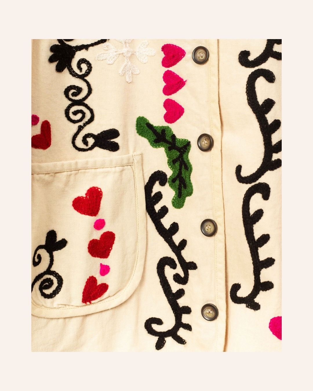 Cream cotton jacket hand-embroidered with black peacock, pink florals, red hearts, and swirling folk-style vines.